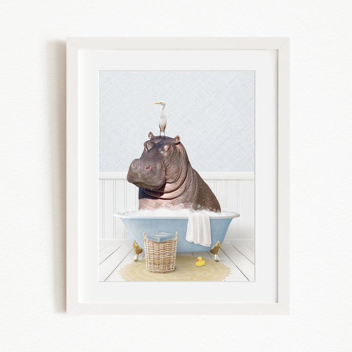 A framed image depicting a large hippopotamus sitting in a bathtub, with a bird perched on its head.
