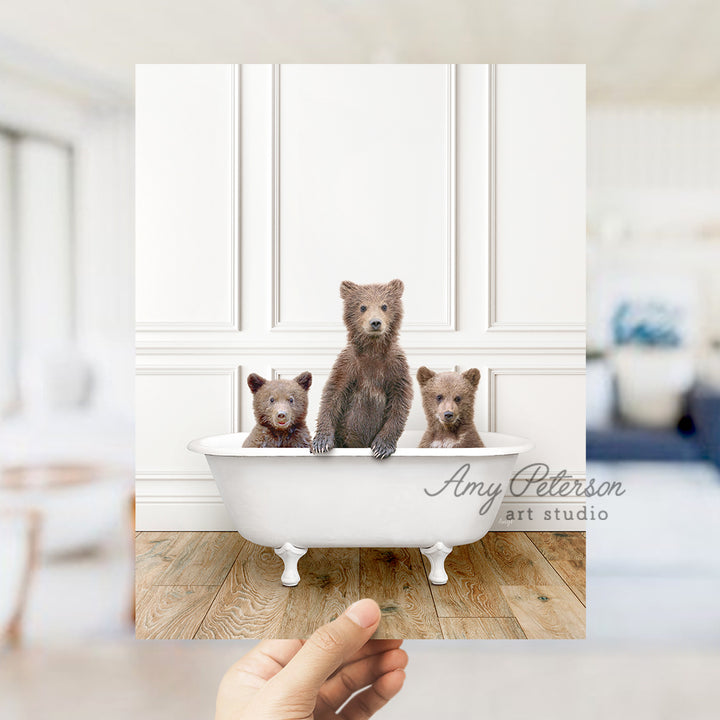 a hand holding a photo of three bears in a bathtub