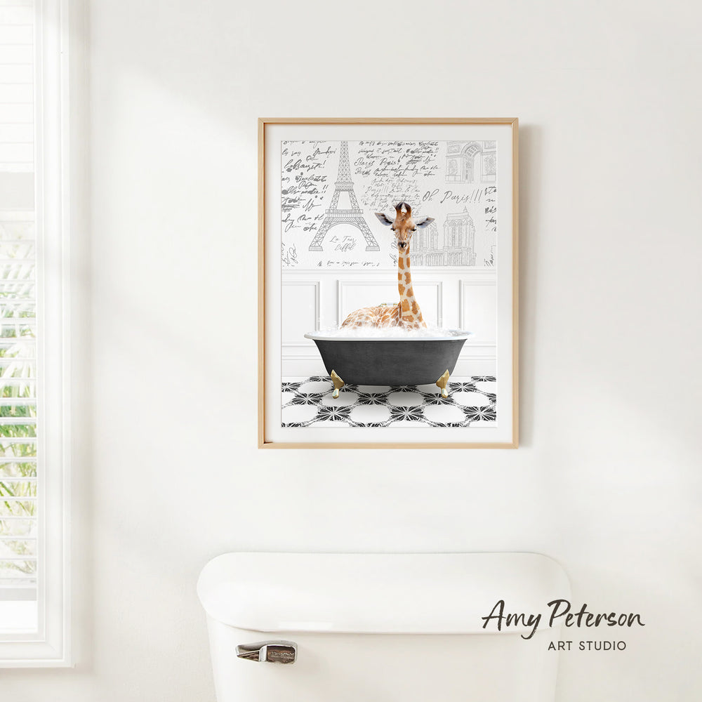 A framed print of a giraffe sitting in a bathtub is hanging on a white wall.