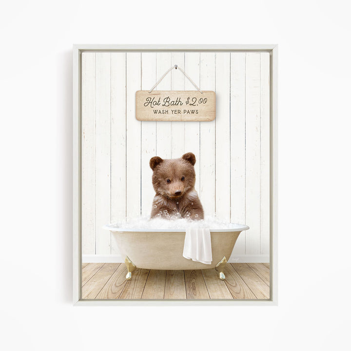 A brown bear sitting in a white bathtub, with a sign above that reads "Hot Bath $2.00 WASH YER Paws".