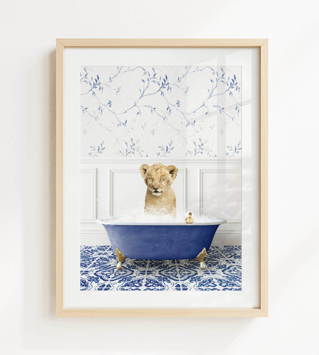 A young lion cub sitting in a blue bathtub filled with bubbles, surrounded by a blue and white floral patterned wall.