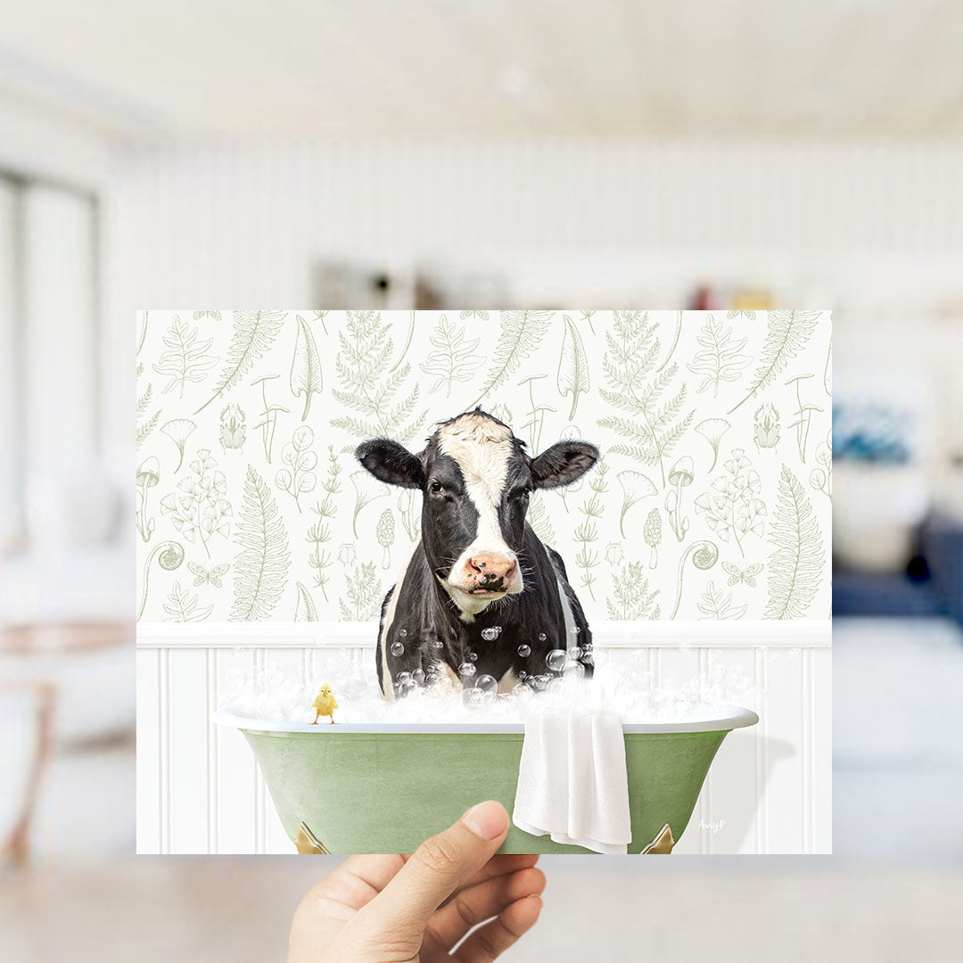 A black and white cow is sitting in a green bathtub filled with bubbles, with a small yellow bird perched on the edge of the tub.