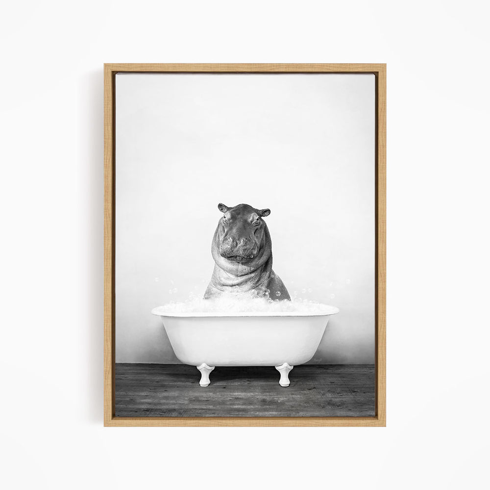 A black and white photograph of a hippopotamus sitting in a bathtub filled with water.