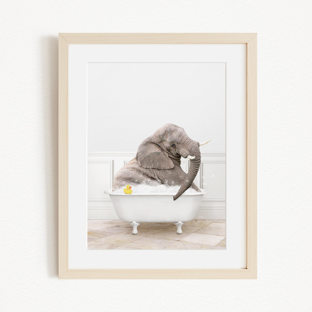 A gray elephant is sitting in a white bathtub, with a yellow rubber duck floating in the water.
