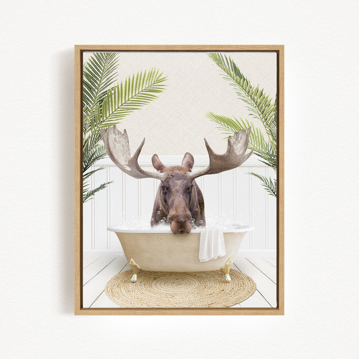 A moose with large antlers is sitting in a bathtub filled with water, surrounded by green leaves.