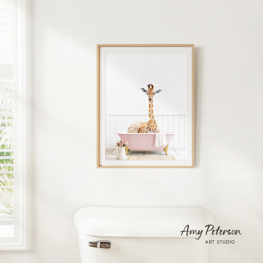 A giraffe sitting in a pink bathtub, with a vase of flowers nearby, is the focus of the image.