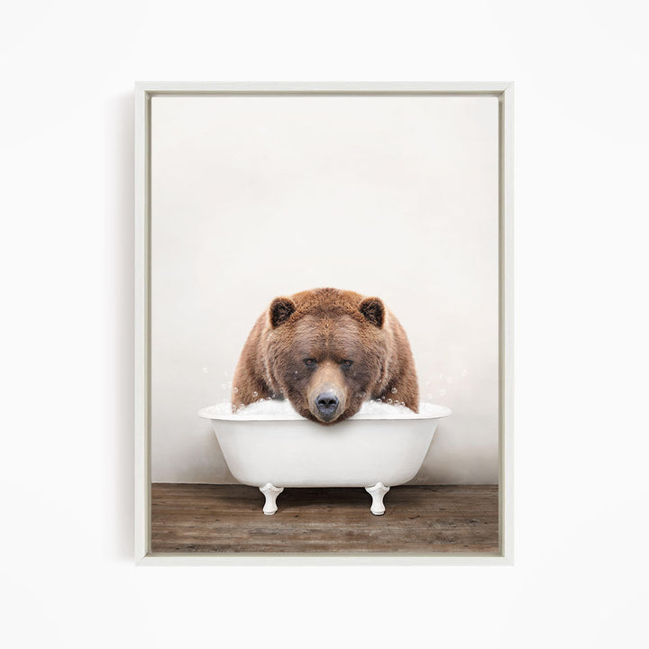 A brown bear sitting in a white bathtub filled with water, appearing to enjoy the bath.