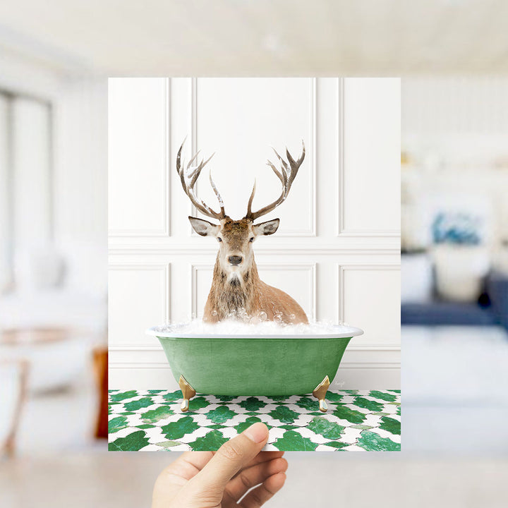 A deer with large antlers is sitting in a green bathtub filled with water, surrounded by a patterned green and white floor.