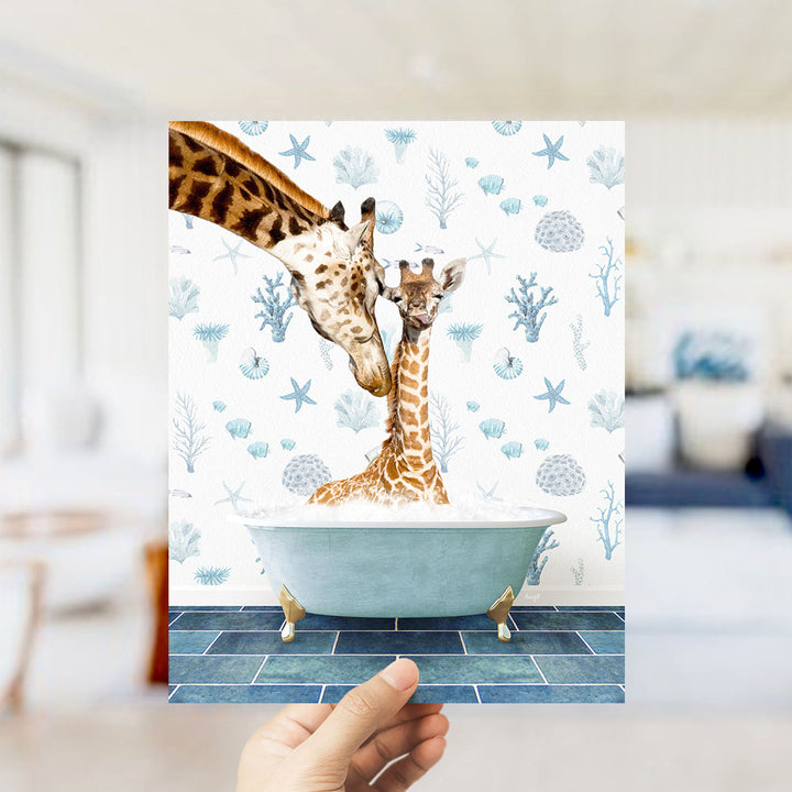 A hand holds up a framed image depicting two giraffes in a bathtub, surrounded by a blue and white ocean-themed wallpaper.