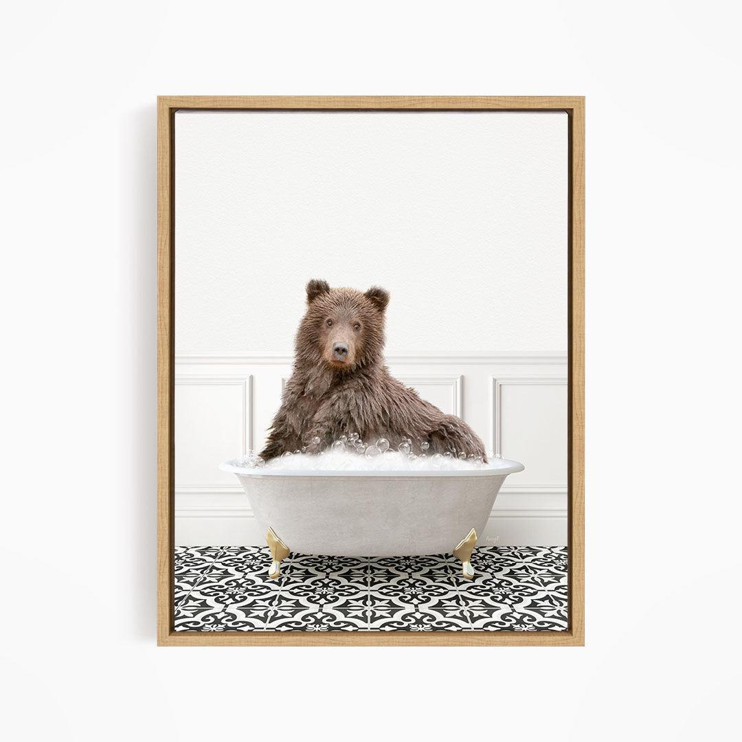 A brown bear sitting in a white bathtub filled with bubbles, looking directly at the camera.