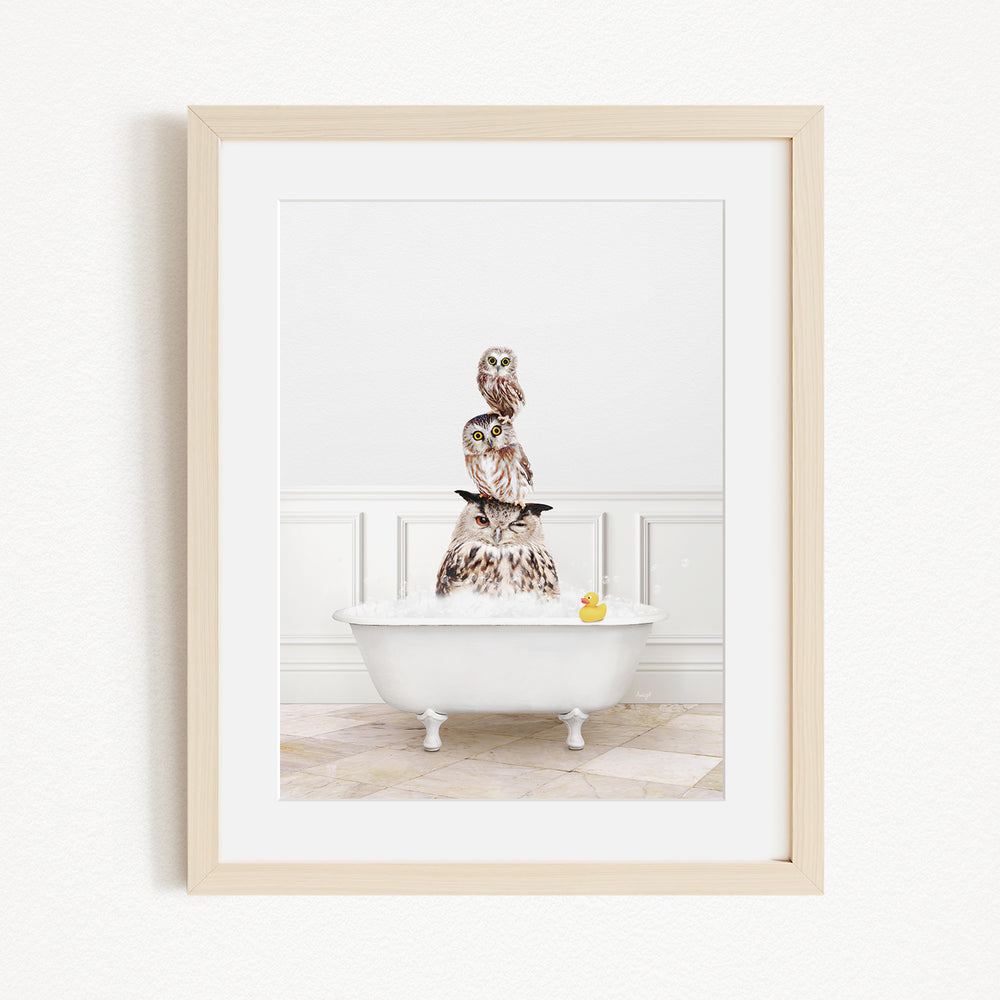 A framed image depicting a white bathtub filled with water, with a stack of owls sitting on top of it.