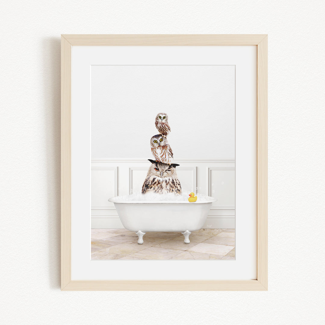 A framed image depicting a white bathtub filled with water, with a stack of owls sitting on top of it.