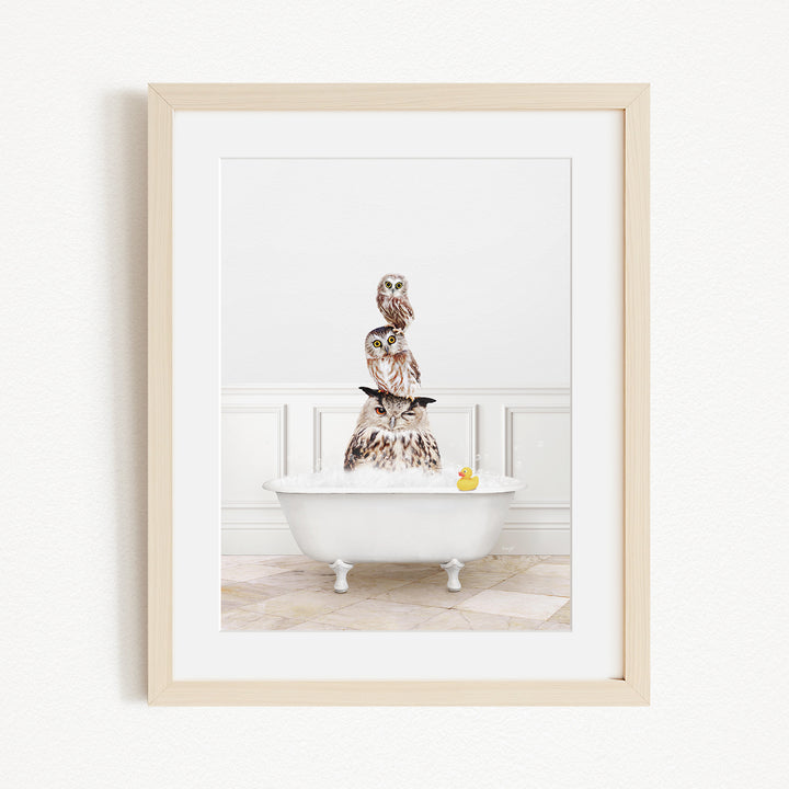 A framed image depicting a white bathtub filled with water, with a stack of owls sitting on top of it.