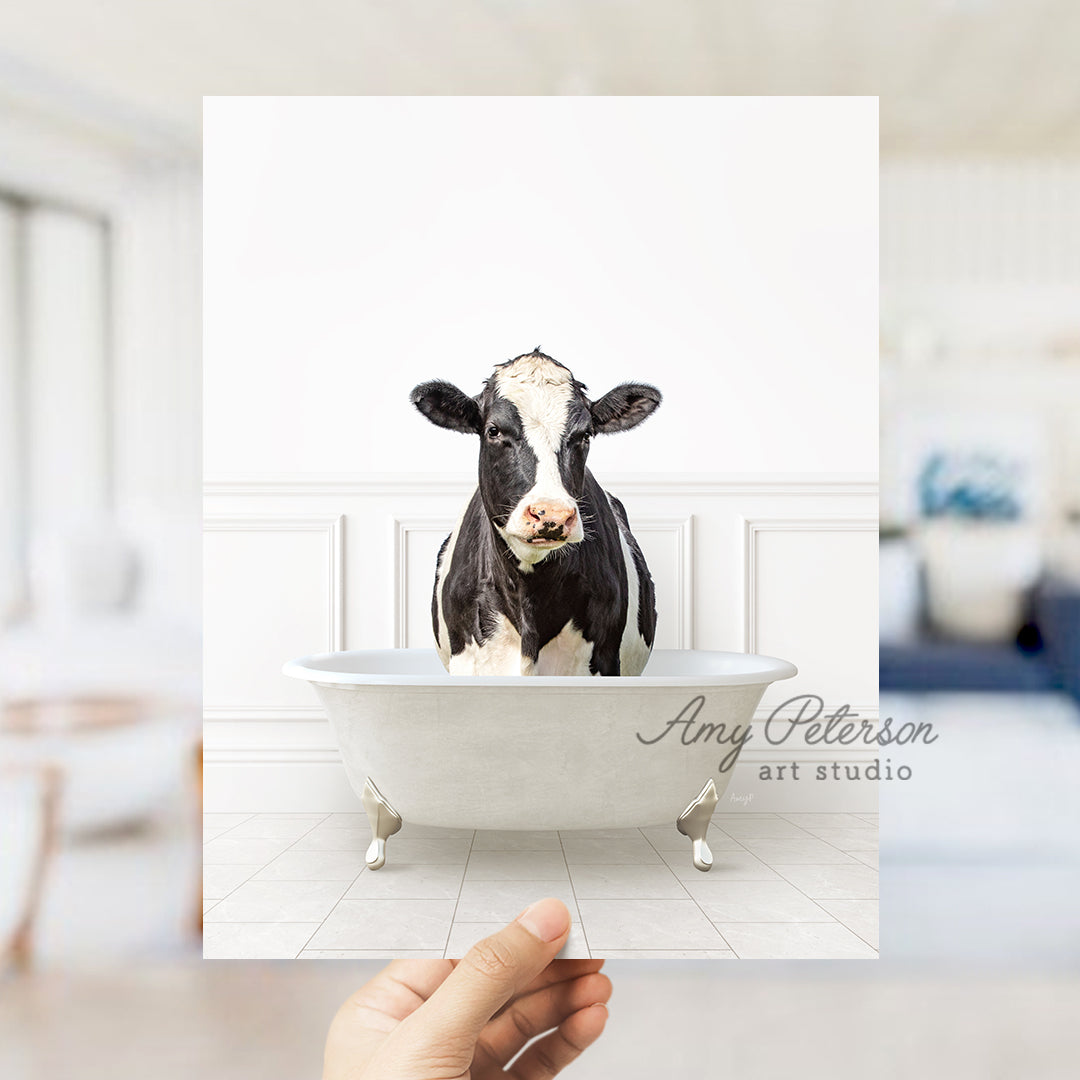 a hand holding up a card with a picture of a cow in a bathtub