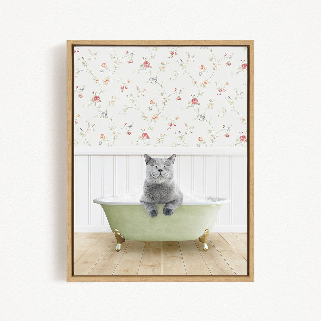 A gray cat sitting in a green bathtub filled with bubbles, with a floral wallpaper in the background.