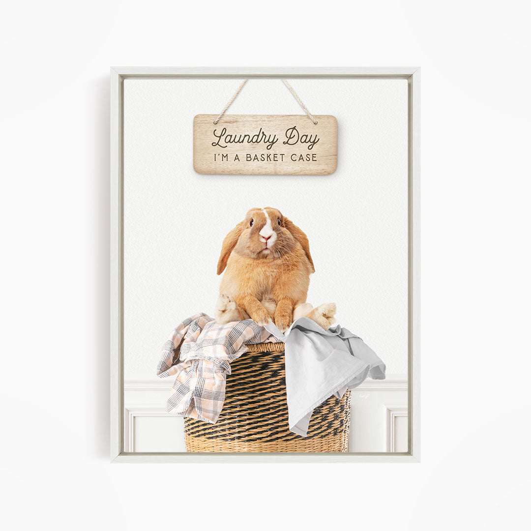 A wooden sign with the text "Laundry Day I'm a basket case" hangs above a woven basket containing a brown rabbit.