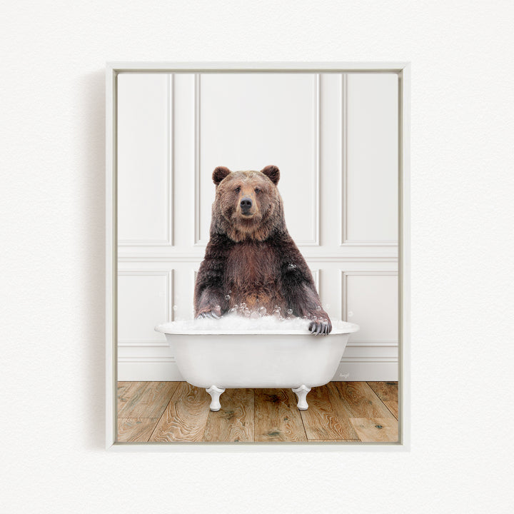 A brown bear sitting in a white bathtub filled with water, appearing to enjoy the bath.