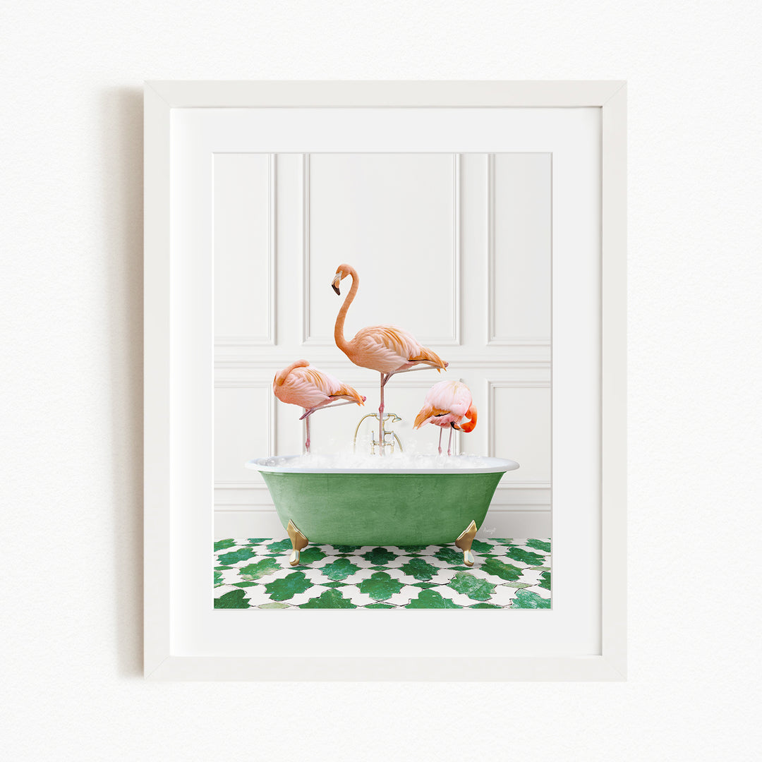 A framed image depicting three pink flamingos standing in a green bathtub on a patterned green and white rug.