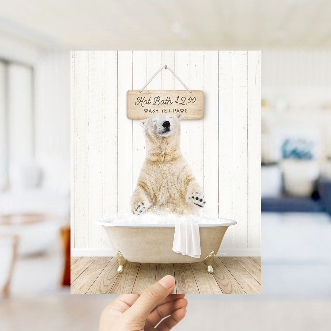 A hand holding a framed image of a polar bear sitting in a bathtub, with a sign above it that says "Hot Bath $2.00 WASH YER PAWS".