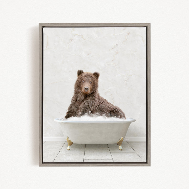 A brown bear sitting in a white bathtub filled with bubbles, looking directly at the camera.