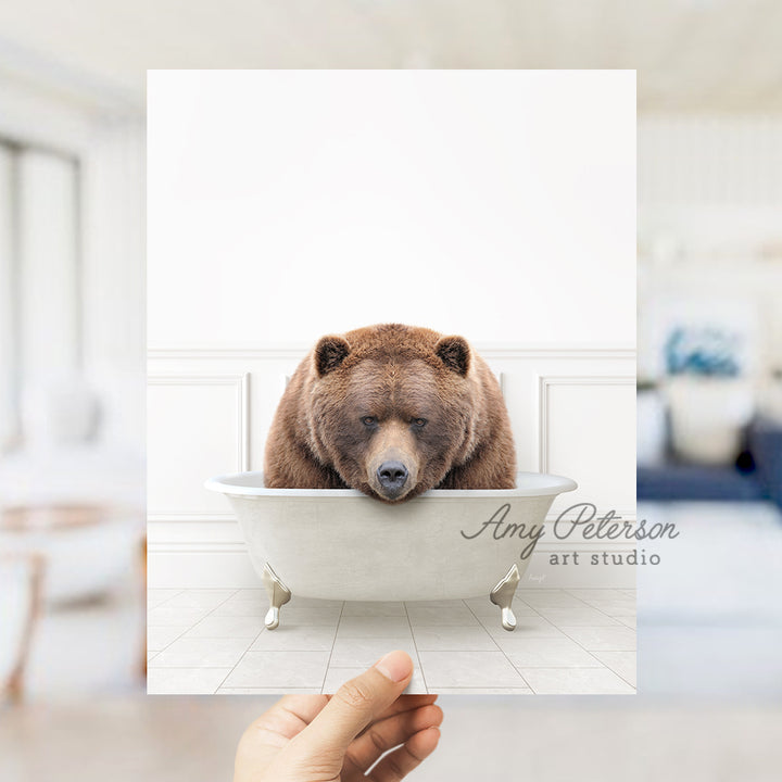 a hand holding a card with a bear in a bathtub