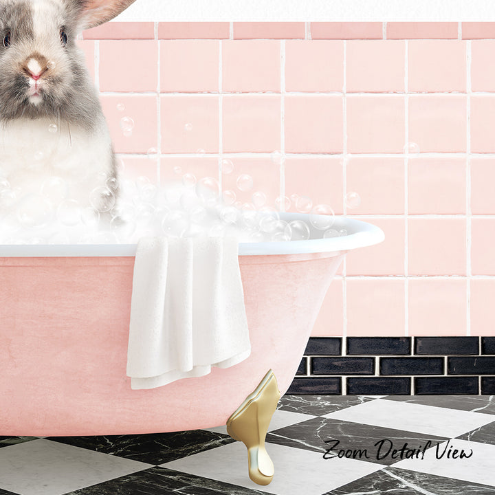 A fluffy white rabbit sitting in a pink bathtub filled with bubbles, with a towel draped over the side and a pink tile wall in the background.