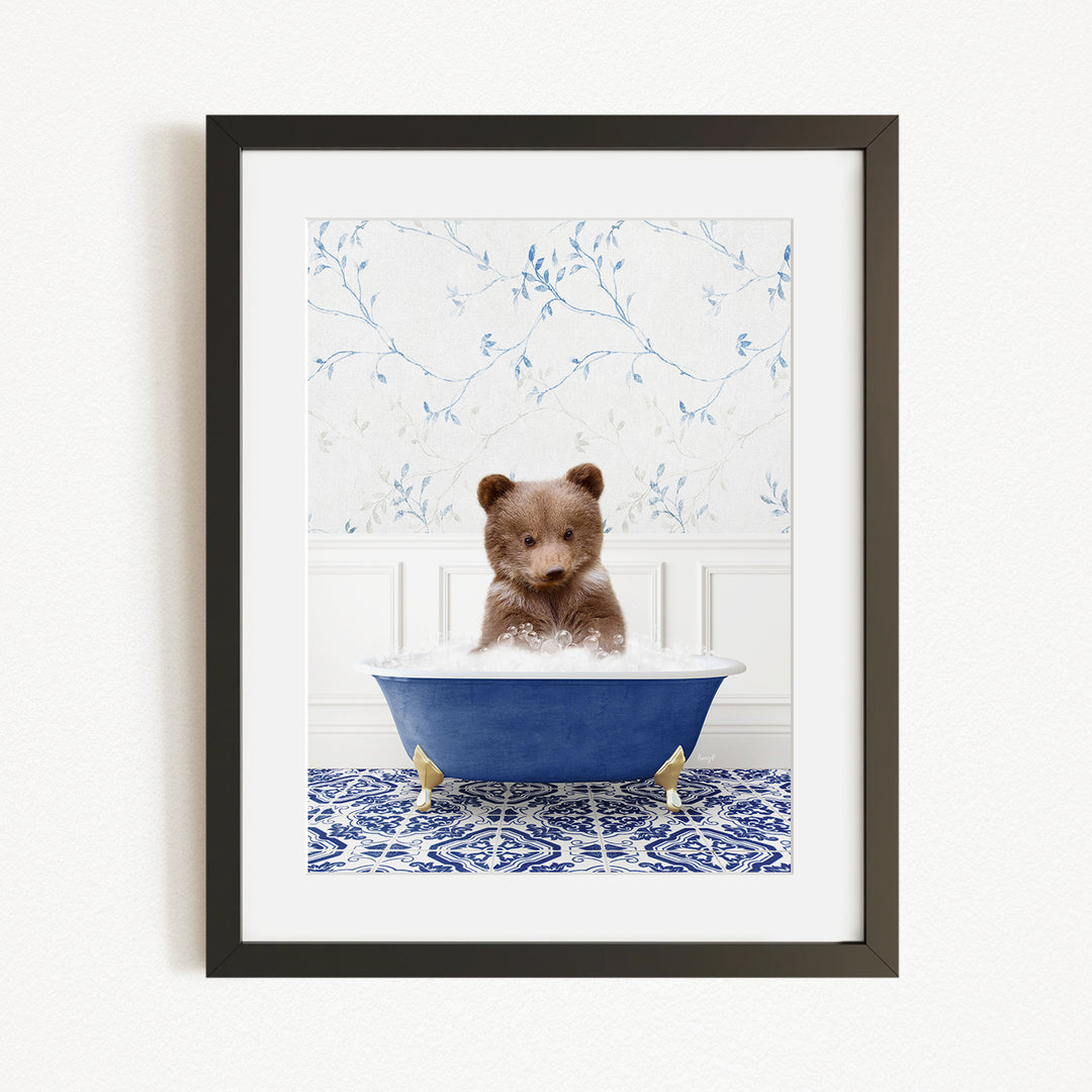 A small brown bear is sitting in a blue bathtub filled with water, surrounded by a blue and white patterned rug on the floor.
