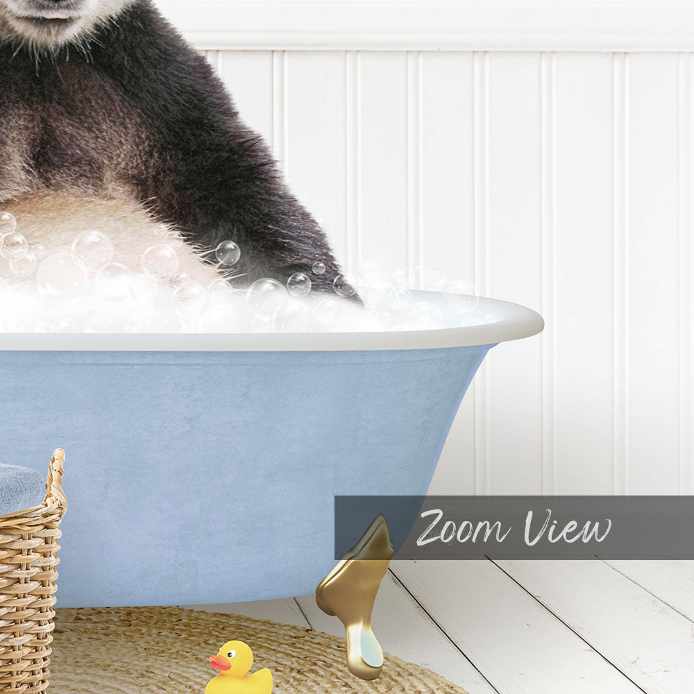 A cat is sitting in a blue bathtub filled with bubbles, with a yellow rubber duck nearby.