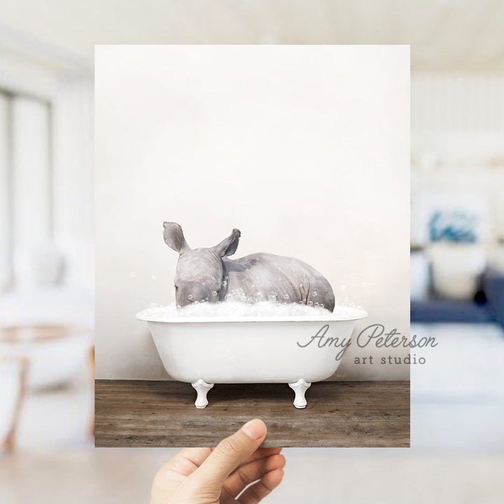 a hand holding a photo of a rhino in a bathtub