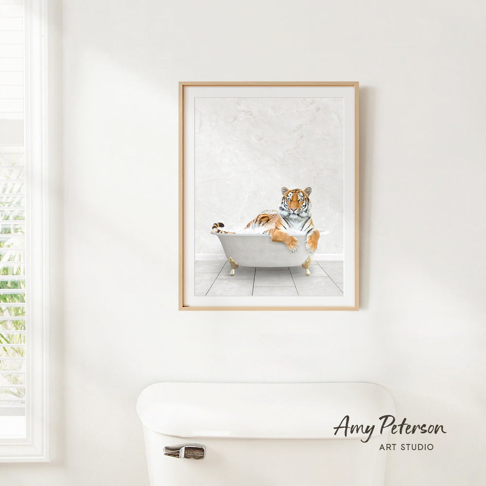 A framed print of a tiger sitting in a bathtub is hanging on a white wall.