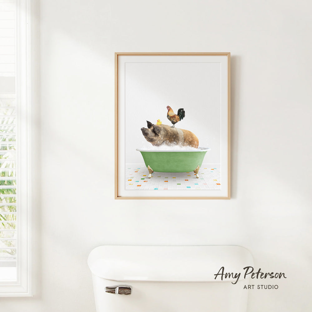 A framed print of a pig sitting in a green bathtub, with a rooster perched on its back, is hanging on a white wall.