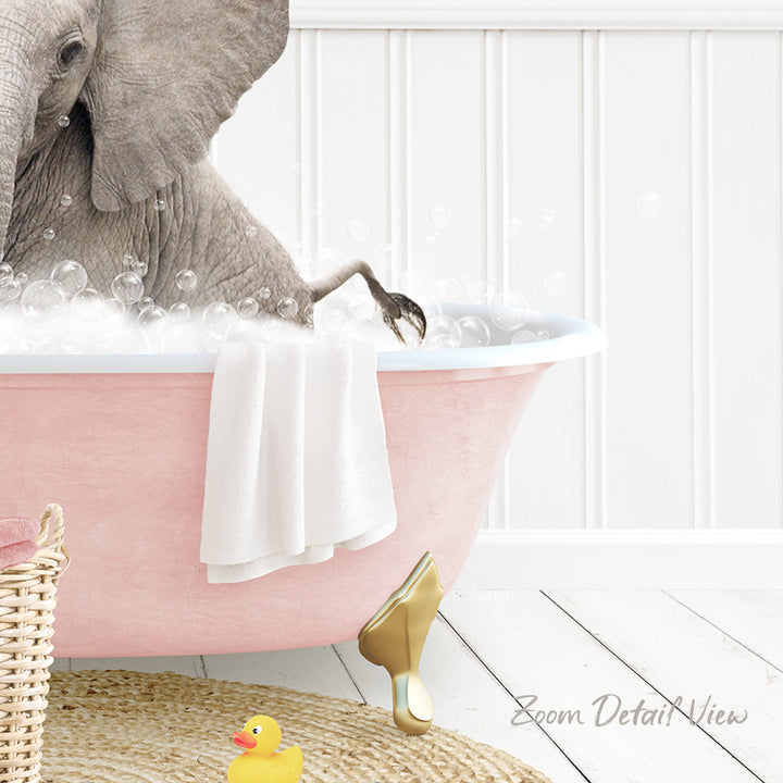 A gray elephant is sitting in a pink bathtub filled with bubbles, surrounded by a yellow rubber duck and a white towel.
