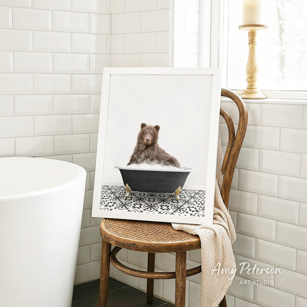 A framed image of a brown bear sitting in a bathtub, surrounded by a black and white patterned tile floor.