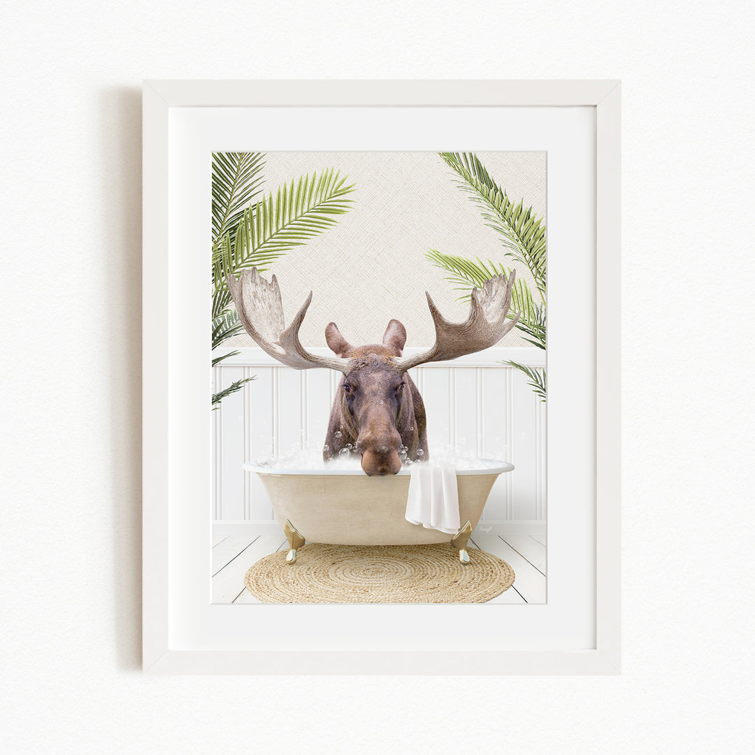A moose with large antlers is sitting in a bathtub, surrounded by green plants.