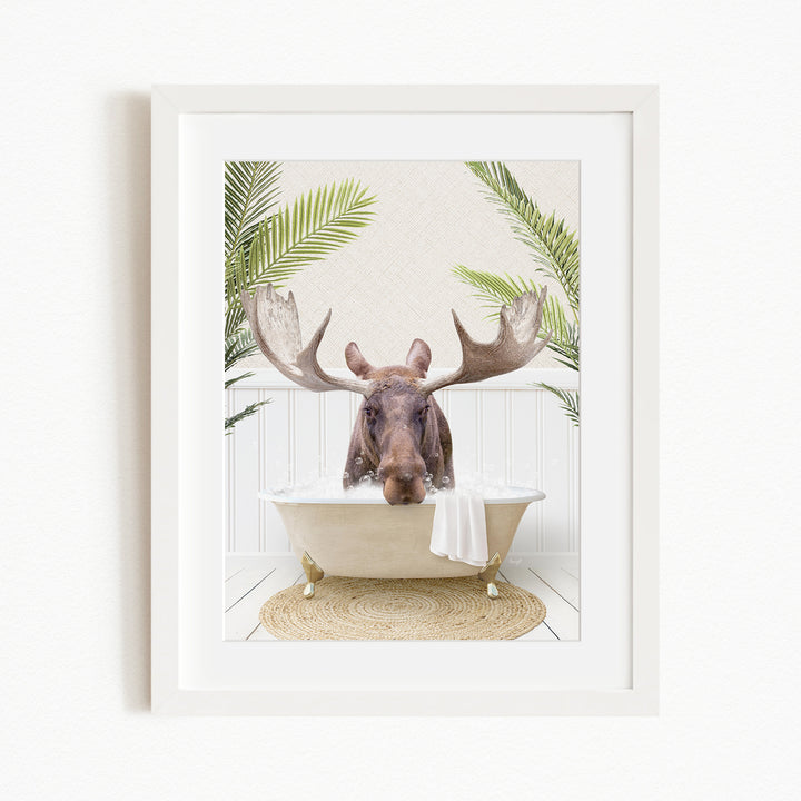 A moose with large antlers is sitting in a bathtub, surrounded by green plants.