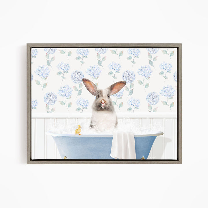 A fluffy white rabbit sits in a blue bathtub filled with bubbles, surrounded by a floral patterned wall.