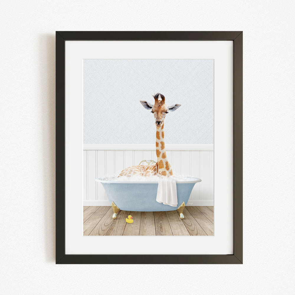 A giraffe standing in a blue bathtub filled with bubbles, with a white towel draped over its neck.