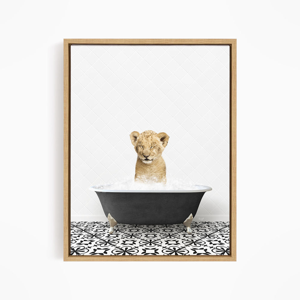 A young lion cub sitting in a bathtub filled with water, looking directly at the camera.