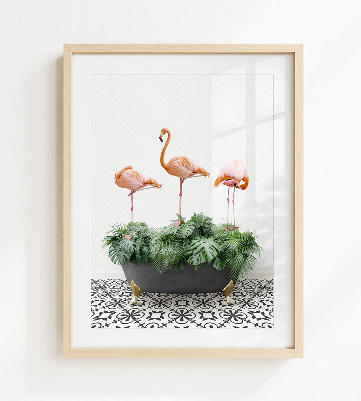 A framed image of three flamingos standing on a black and white patterned surface, with a potted plant in the foreground.
