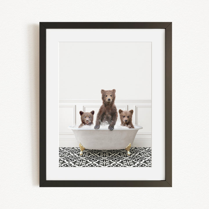 A framed image depicting three bears sitting in a bathtub filled with water, with a patterned rug on the floor beneath them.