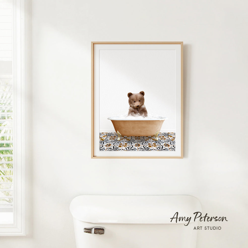 A framed image of a baby bear sitting in a bathtub, surrounded by a patterned design on the floor.