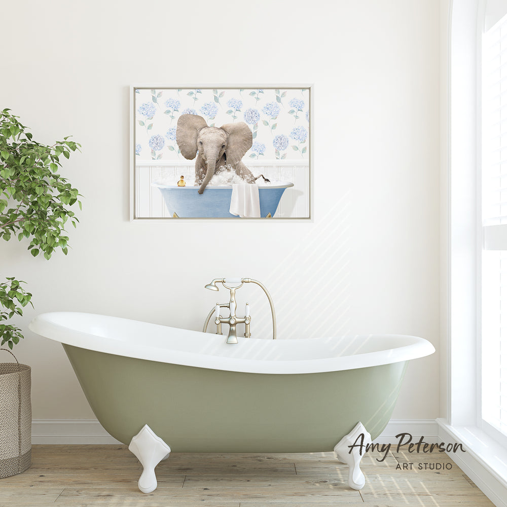 A green clawfoot bathtub with a framed image of an elephant sitting in it, hanging on a white wall above it.