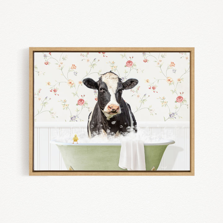 A black and white cow is sitting in a green bathtub filled with bubbles, with a yellow bird perched on the edge of the tub.