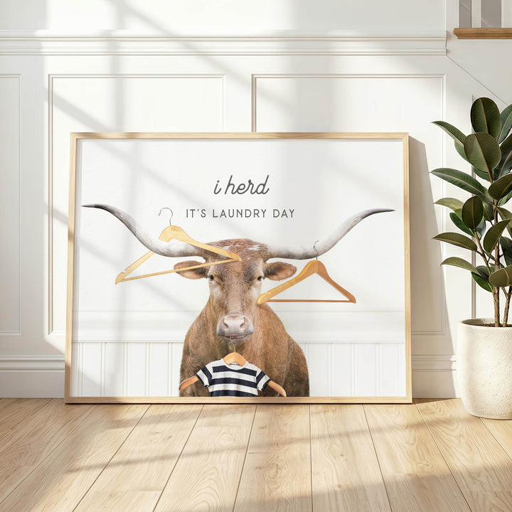 A framed poster with a bull's head and a shirt, along with the text "It's laundry day" and a humorous caption about laundry day.