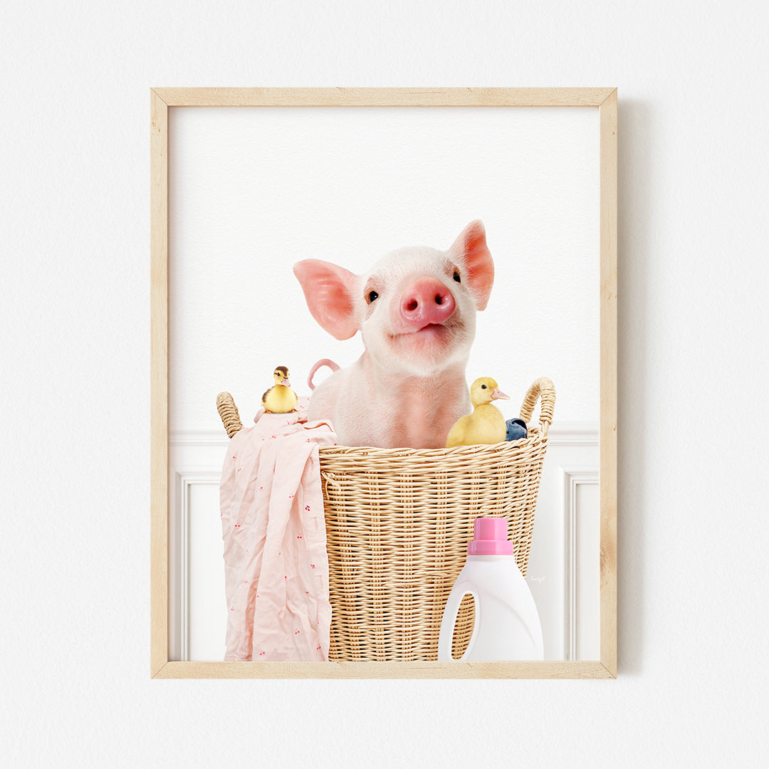 a pig sitting in a basket with a pink towel