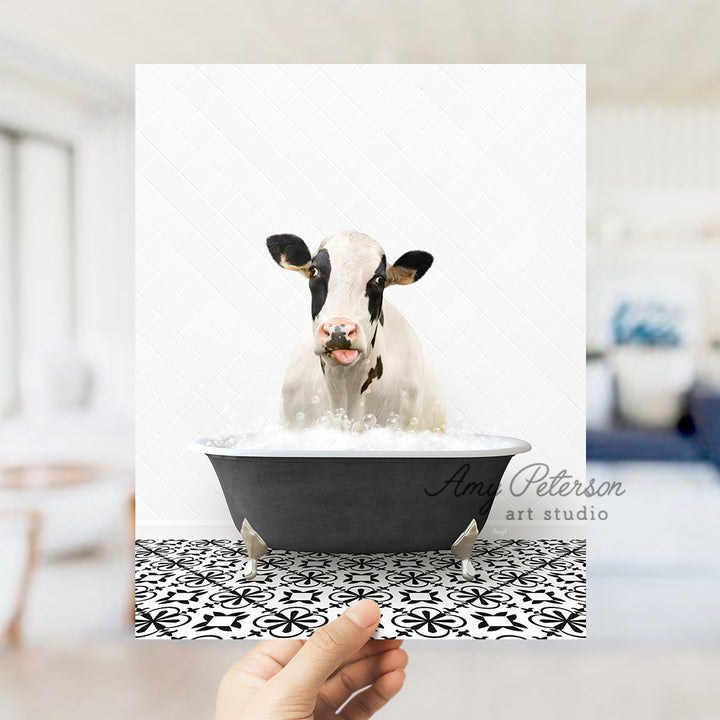 a person holding up a picture of a cow in a bathtub