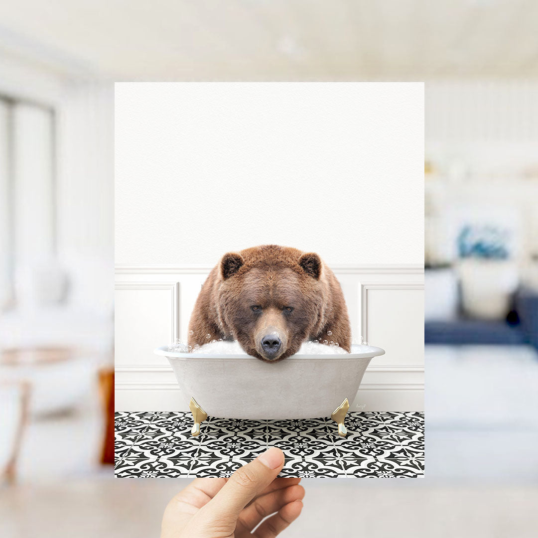 A brown bear sitting in a white bathtub filled with water, with a hand holding the image up to the camera.
