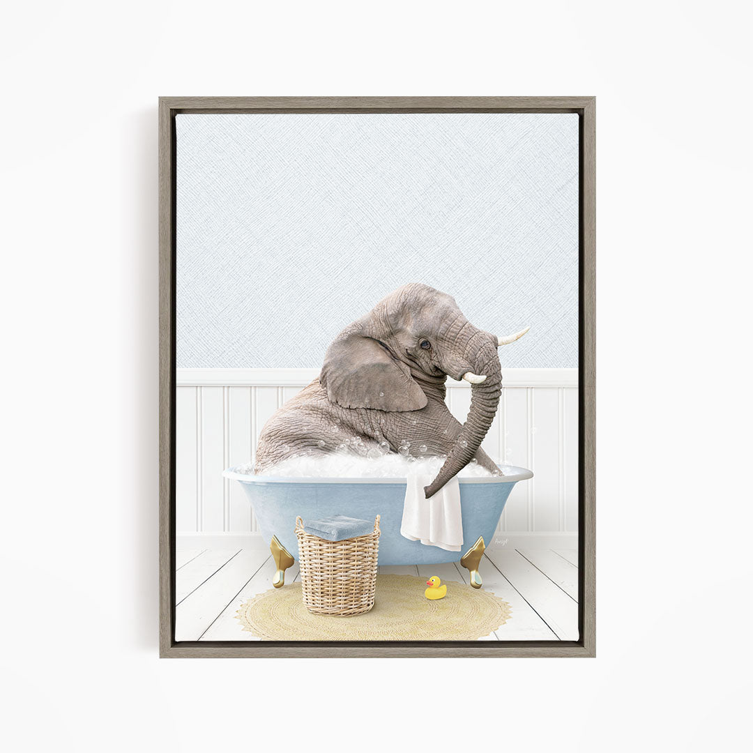 A gray elephant is sitting in a blue bathtub filled with water, surrounded by a yellow rubber duck and a basket.