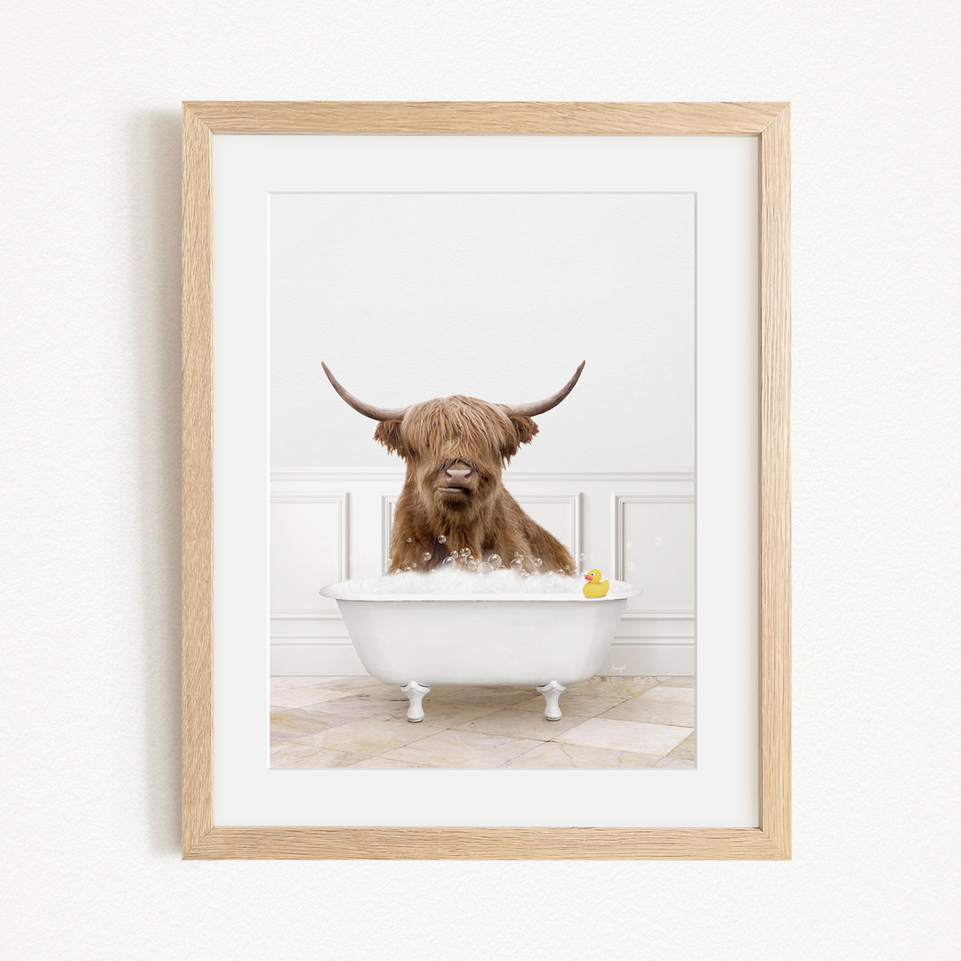 A brown Highland cow with large horns is sitting in a white bathtub filled with water, with a yellow rubber duck floating in the tub.