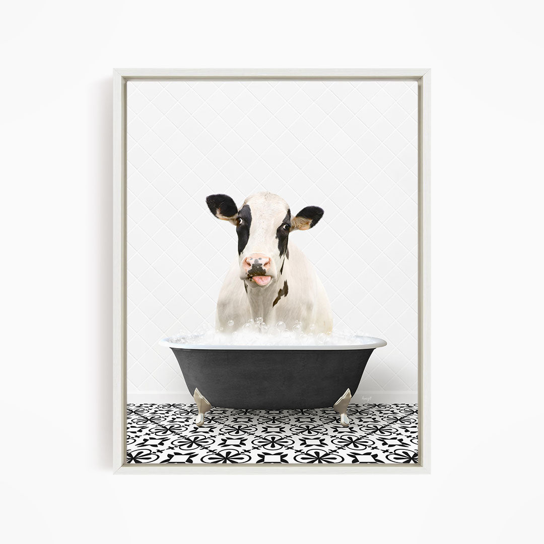 A black and white cow is sitting in a black bathtub filled with water, appearing to enjoy the bath.